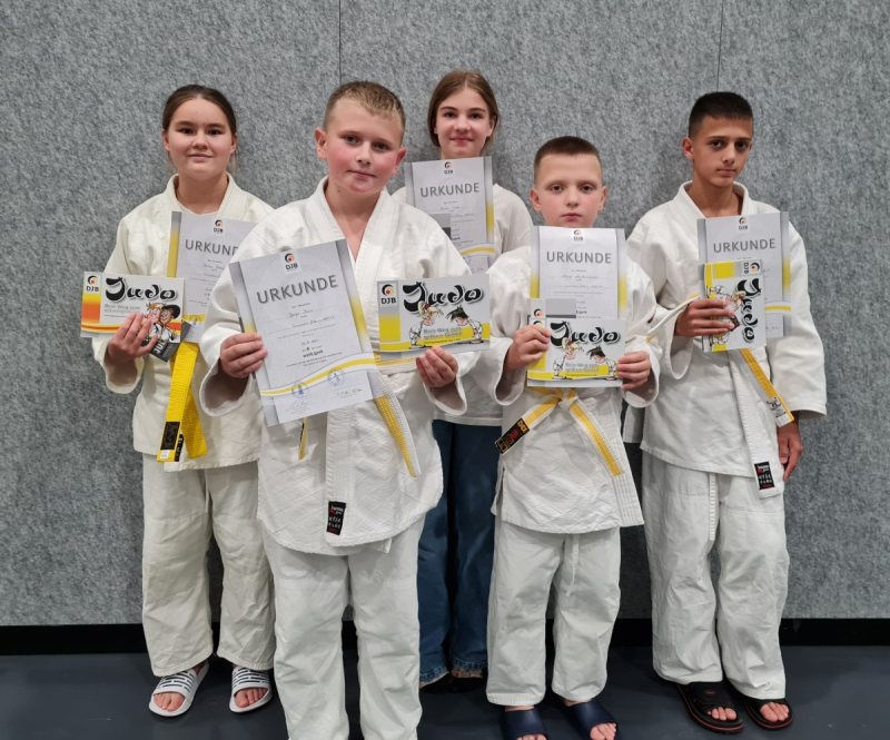 Kinder in Judoanzügen posieren mit ihren Urkunden